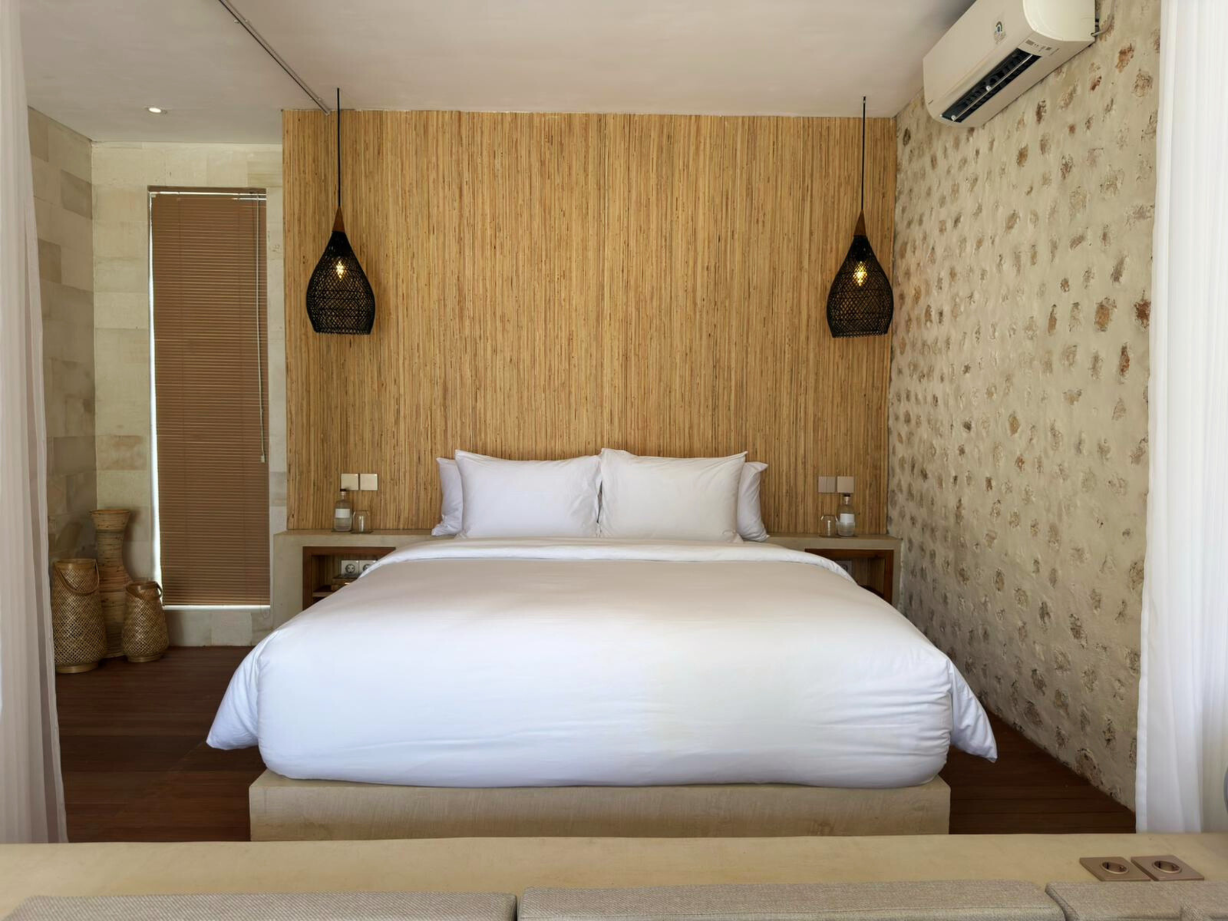 Symmetrisch frontaal zicht op het bed met twee nachtkastjes en hanglampen; airco boven het bed