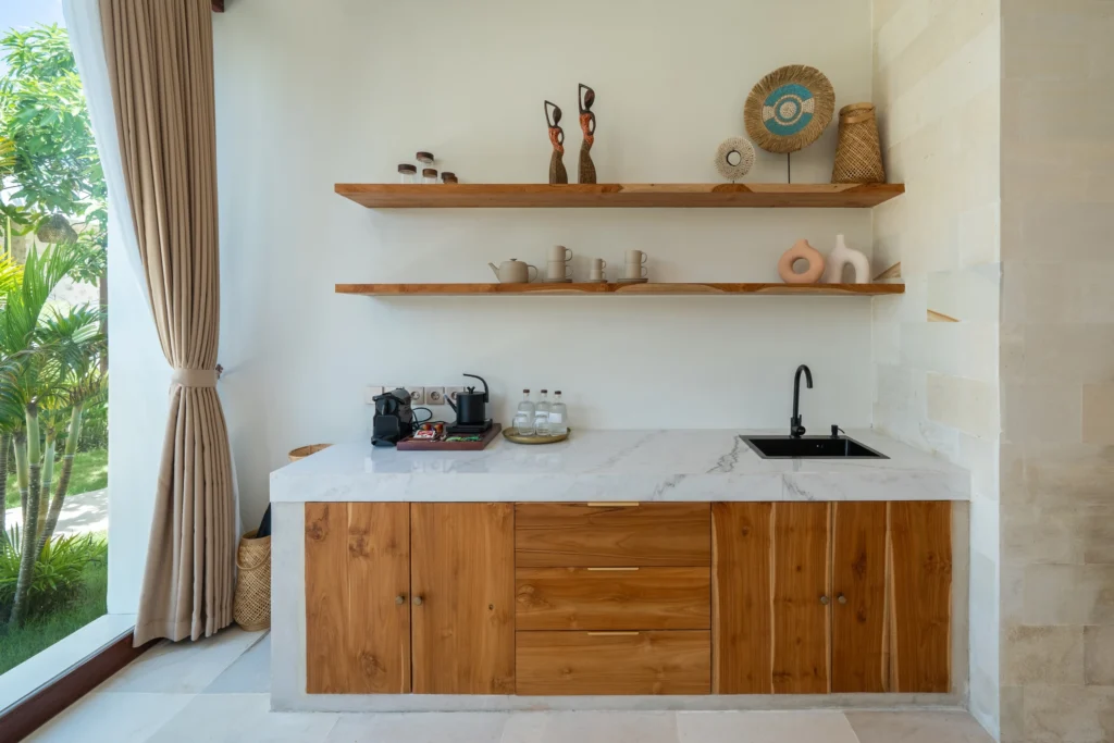 Close‑up van het bed met bamboe hoofdbord, stenen muren, zwarte hanglampen en ingebouwde plank met waterkaraf