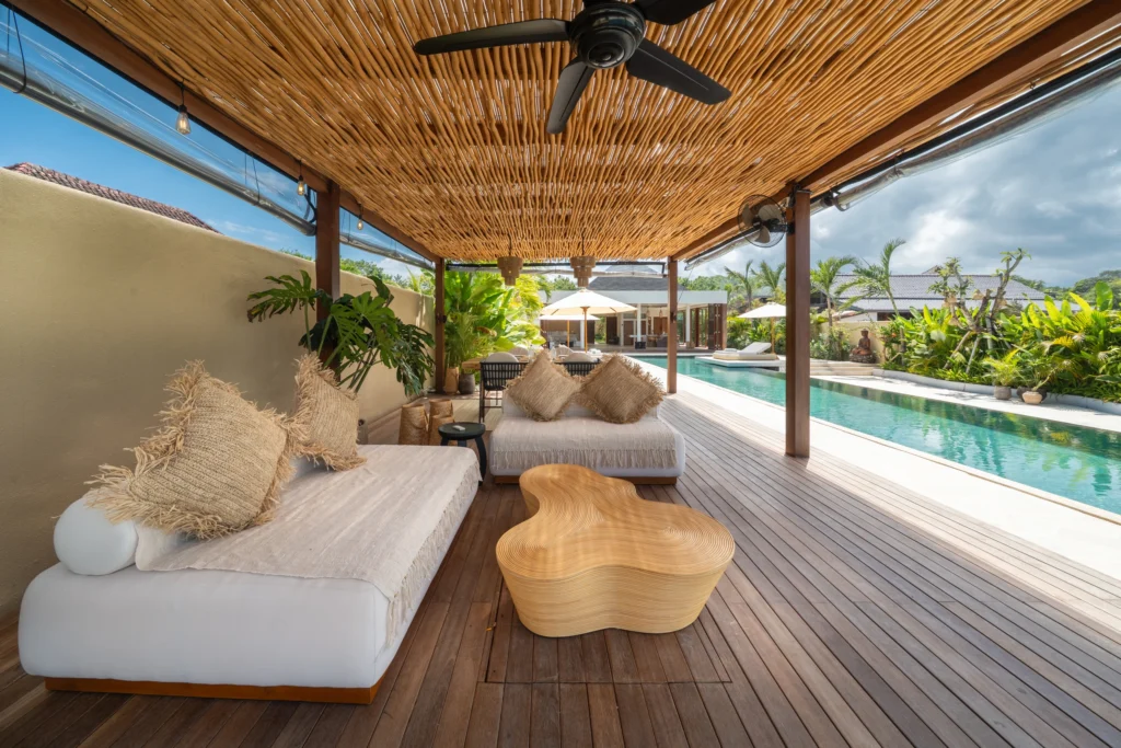 Lang tuinpad langs de villa met palmen en tropische planten; glaspui met uitzicht op zee in de verte