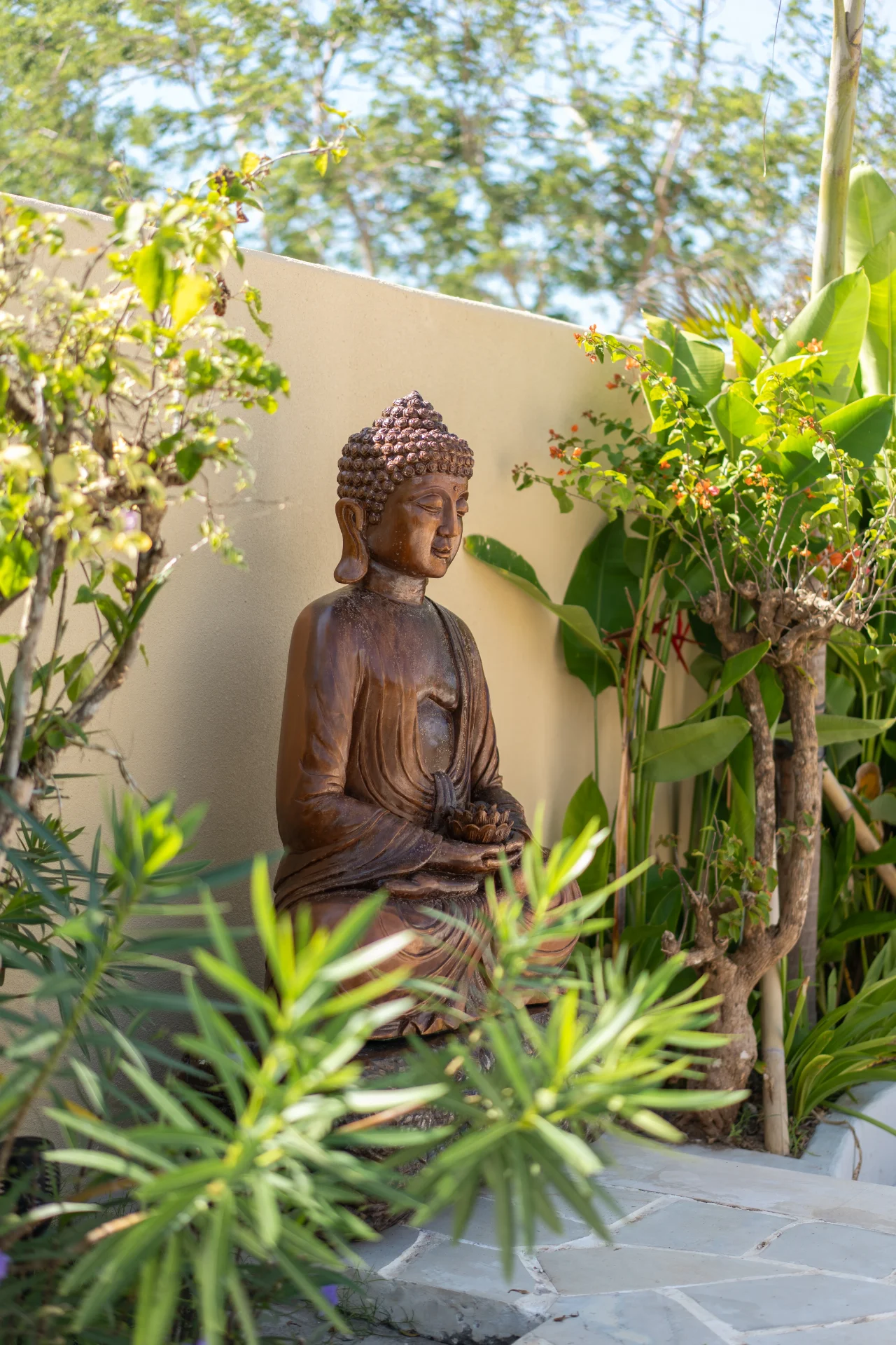 Carved wooden Buddha framed by tropical greenery