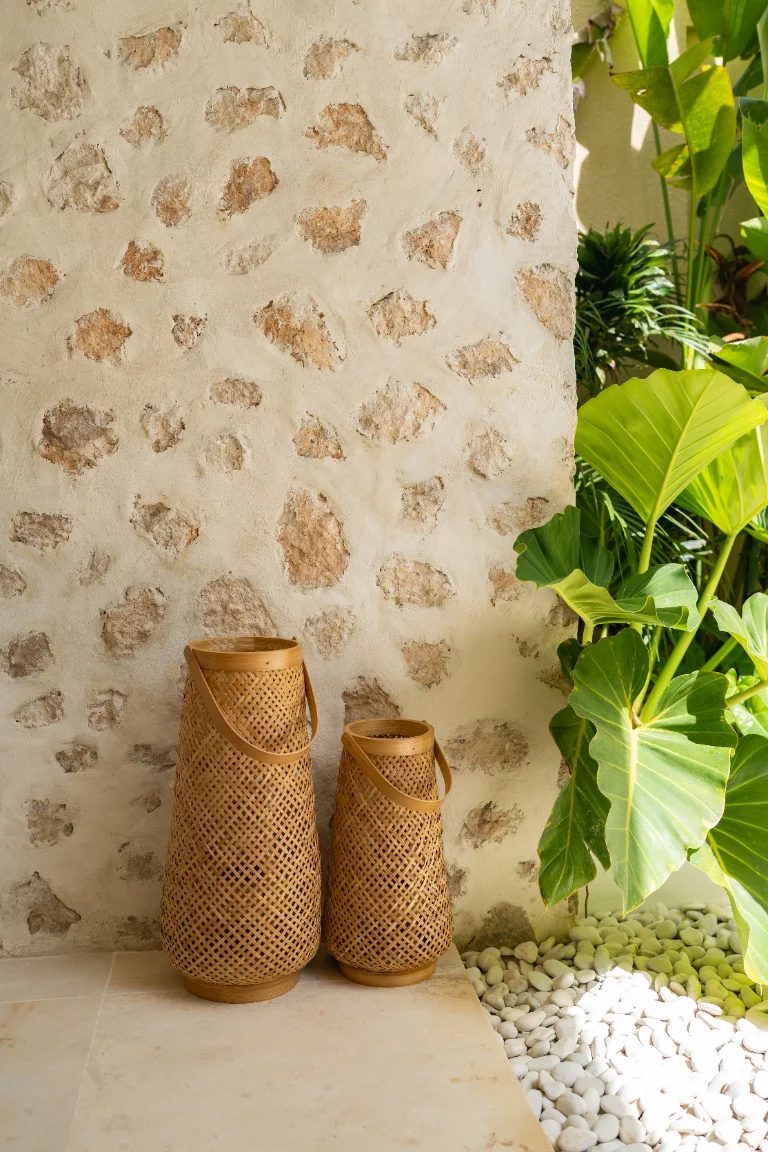 Detail of the natural stone wall with woven lanterns and foliage