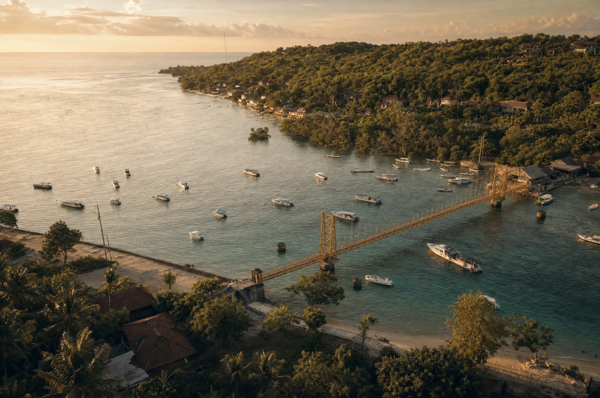 Aerial view at golden hour of the Yellow Bridge linking Nusa Lembongan to Nusa Ceningan, with boats moored in the turquoise channel below